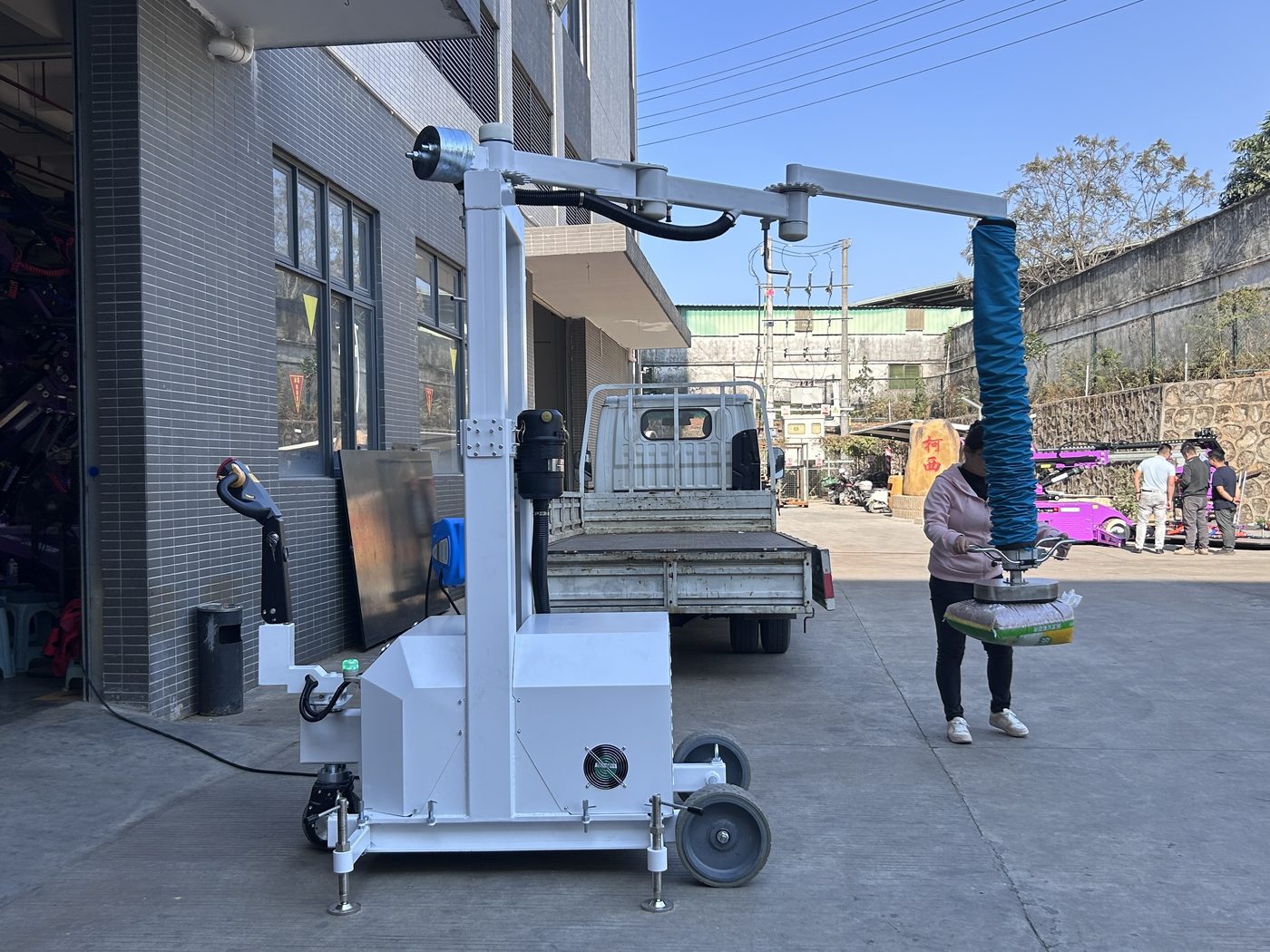 Mobile vacuum tube lifter holding a sack beside a truck