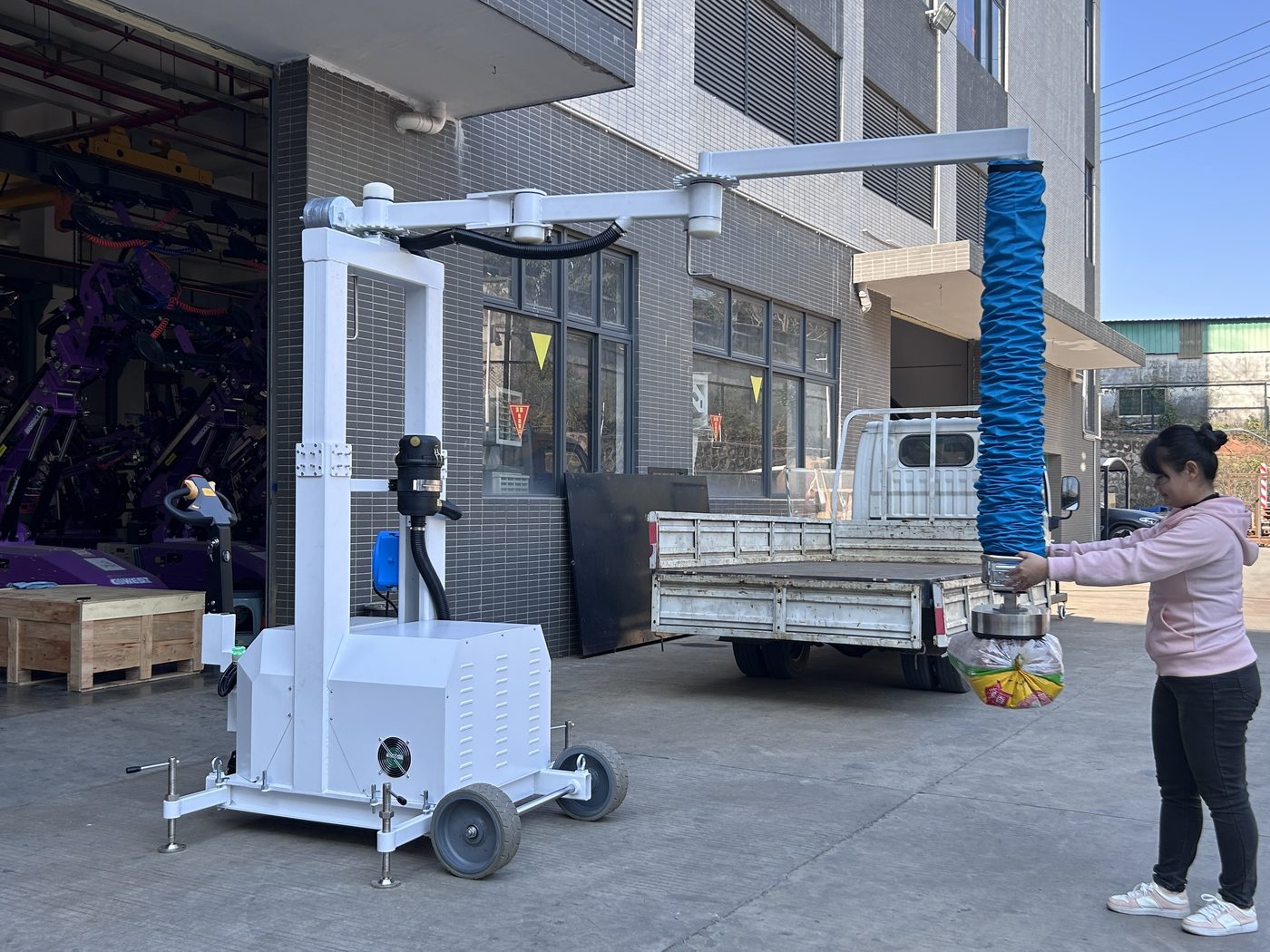 Operator lifting a sack with a mobile vacuum tube lifter in the yard
